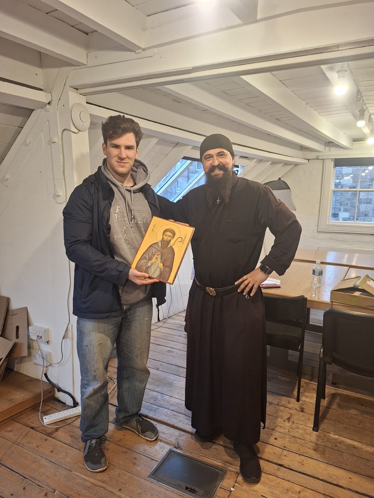 A student holding a finished icon beside Father Ilie